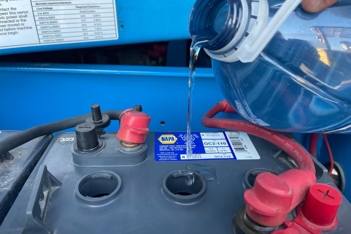 zoom on a someone adding distilled water in a battery